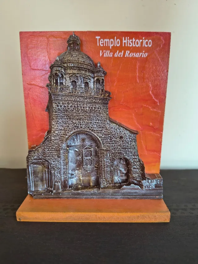 Placa en relieve del Templo Histórico de Villa del Rosario sobre fondo naranja