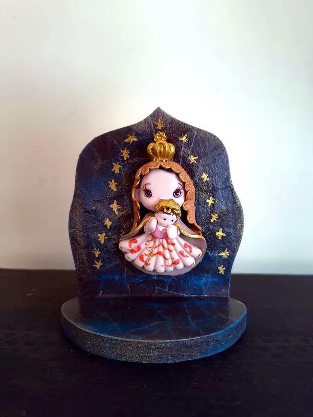 Figura de la Virgen con el Niño modelada a mano sobre un retablo azul con estrellas doradas