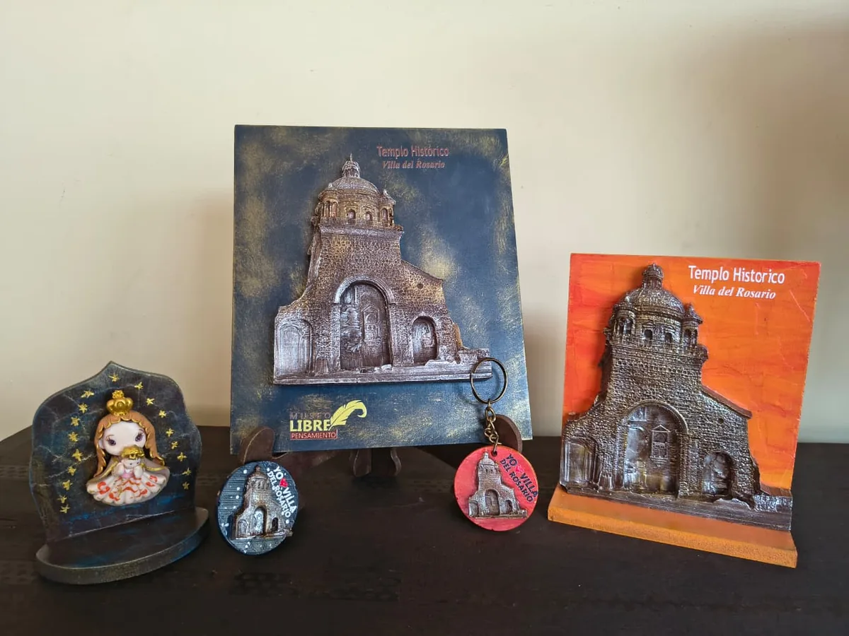 Placas en relieve del Templo Histórico en azul y naranja, un imán, un llavero y una figura de la Virgen sobre una mesa