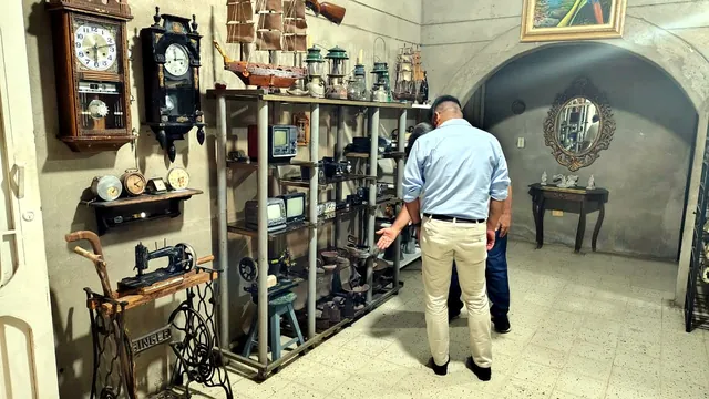Sala del museo con relojes de pared, televisores pequeños y una máquina de coser Singer